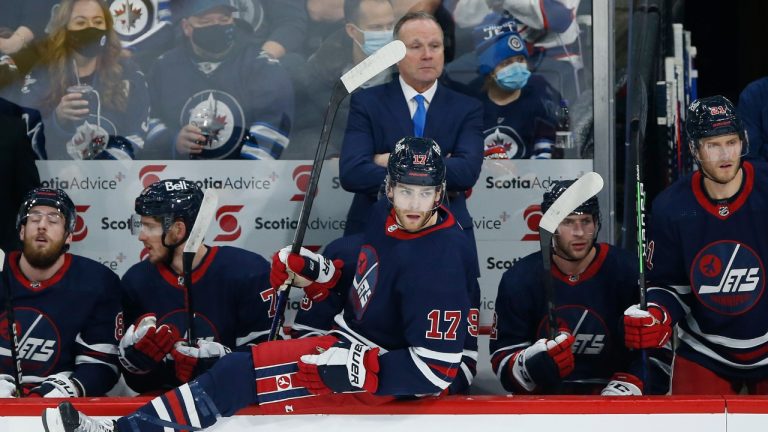 Winnipeg Jets' Adam Lowry (17) goes over the boards as his father, the new interim head coach, Dave Lowry, looks on against the Washington Capitals during first period NHL action in Winnipeg on Friday, December 17, 2021. (John Woods/CP)