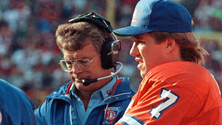 In this Aug. 19, 1989, file photo, Denver Broncos quarterback John Elway, right, and coach Dan Reeves stand on the sideline during the team's NFL preseason football game against the San Francisco 49ers in San Francisco, Calif. (Paul Sakuma/AP) 