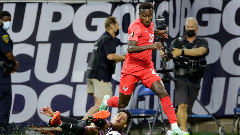 Mexico defender Edson Alvarez, left, falls as he attempts a steal from Canada defender Richie Laryea (22) during the first half of a CONCACAF Gold Cup soccer semifinal Thursday, July 29, 2021. (Michael Wyke/AP)