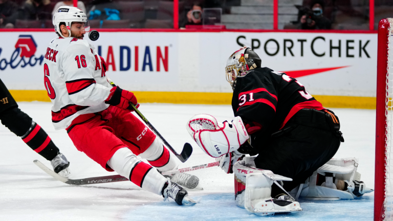 The puck bounces back into the visor of Carolina Hurricanes centre Vincent Trocheck after a poke-check by Ottawa Senators goaltender Anton Forsberg during third period action in Ottawa, on Tuesday, Feb. 8, 2022. (CP)