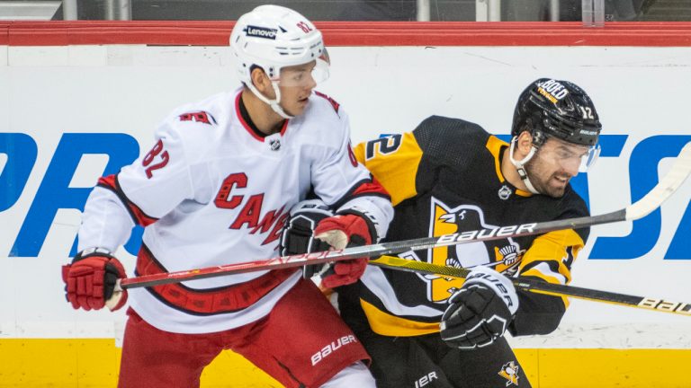 Carolina Hurricanes centre Jesperi Kotkaniemi, 82, and Pittsburgh Penguins winger Zach Aston-Reese, 12, battle for position during the first period of an NHL hockey game against the Carolina Hurricanes and Pittsburgh Penguins on Sunday, Feb. 20, 2022, in Pittsburgh. (Fred Vuich/AP)