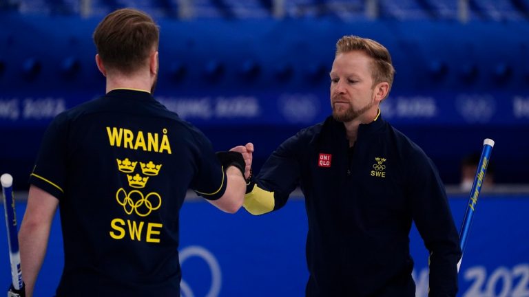 Sweden's Rasmus Wranaa, left and Sweden's Niklas Edin encourage each other during the men's curling final match between Britain and Sweden at the Beijing Winter Olympics Saturday, Feb. 19, 2022, in Beijing. (Brynn Anderson/AP Photo)