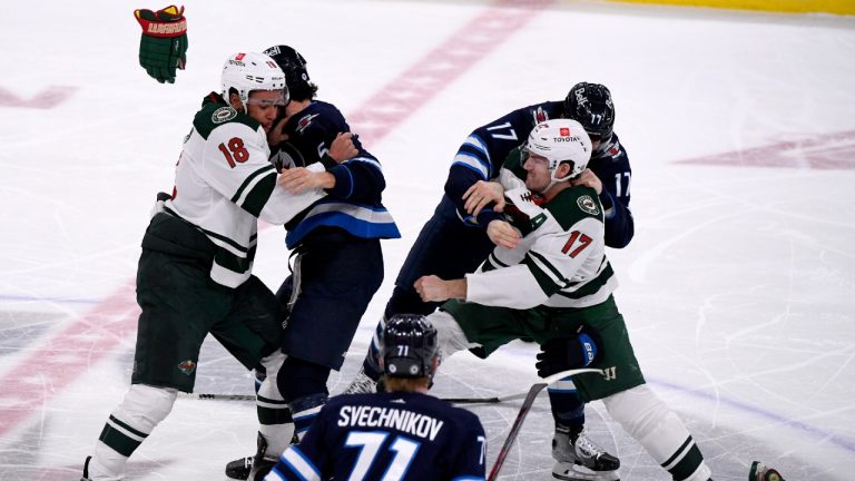 Minnesota Wild's Jordan Greenway (18) and Marcus Foligno (17) fight Winnipeg Jets' Brenden Dillon (5) and Adam Lowry (17) during the first period of NHL action in Winnipeg on Tuesday February 8, 2022. (Fred Greenslade/CP)