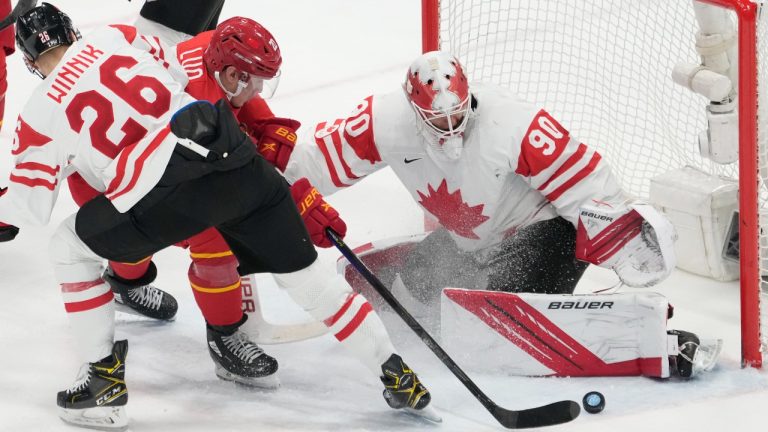 China forward Luke Lockhart (20) is stopped by Canada goaltender Matt Tomkins (90) and teammate Daniel Winnik (26) during second period men's ice hockey action at the Beijing Olympic Winter Games, in Beijing, Sunday, Feb. 13, 2022. (Ryan Remiorz/THE CANADIAN PRESS)