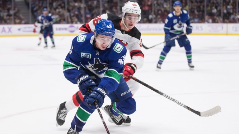 Vancouver Canucks' Quinn Hughes, front, and his brother New Jersey Devils' Jack Hughes, back, vie for the puck. (Darryl Dyck/CP)