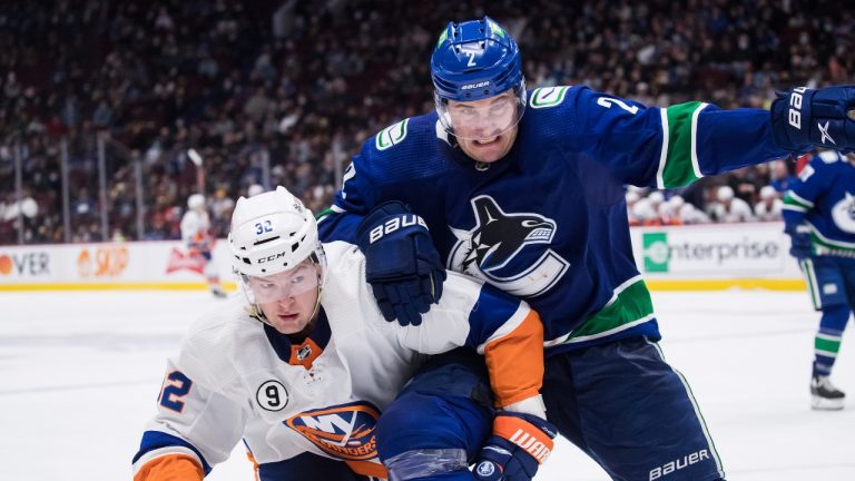 New York Islanders' Ross Johnston (32) and Vancouver Canucks' Luke Schenn (2) vie for the puck during the third period of an NHL hockey game in Vancouver, on Wednesday, February 9, 2022. (Darryl Dyck/THE CANADIAN PRESS)