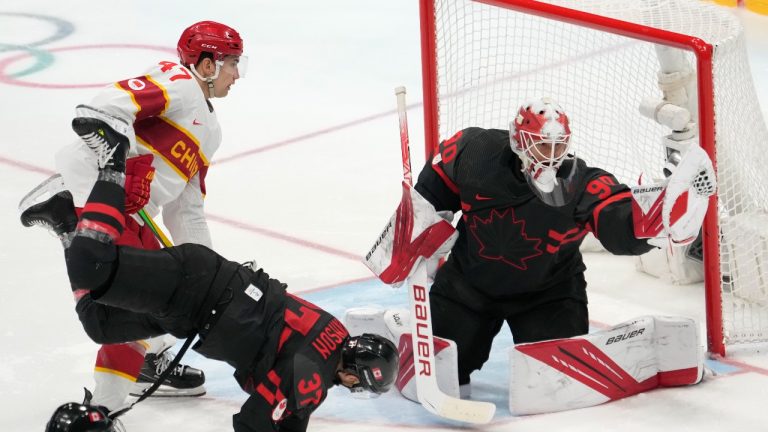 Team Canada goaltender Matt Tomkins (90) makes a save as Team China forward Cory Kane (47) looks on and Canada's Mat Robinson (37) falls during third period men's qualification round hockey action at the Beijing Winter Olympics in Beijing, China, on Tuesday, Feb. 15, 2022. (Ryan Remiorz/THE CANADIAN PRES)