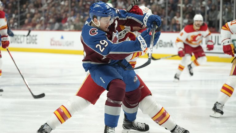 Colorado Avalanche centre Nathan MacKinnon, front, is checked by Calgary Flames defenceman Michael Stone in the third period of an NHL hockey game. (David Zalubowski/AP)