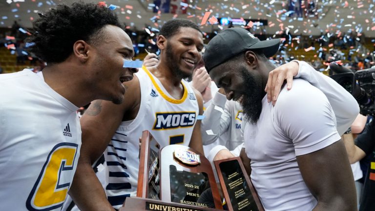 Chattanooga guard David Jean-Baptiste, right, is congratulated by teammates as he holds the championship trophy after his team defeated Furman in an NCAA college basketball championship game for the Southern Conference tournament. (Kathy Kmonicek/AP)