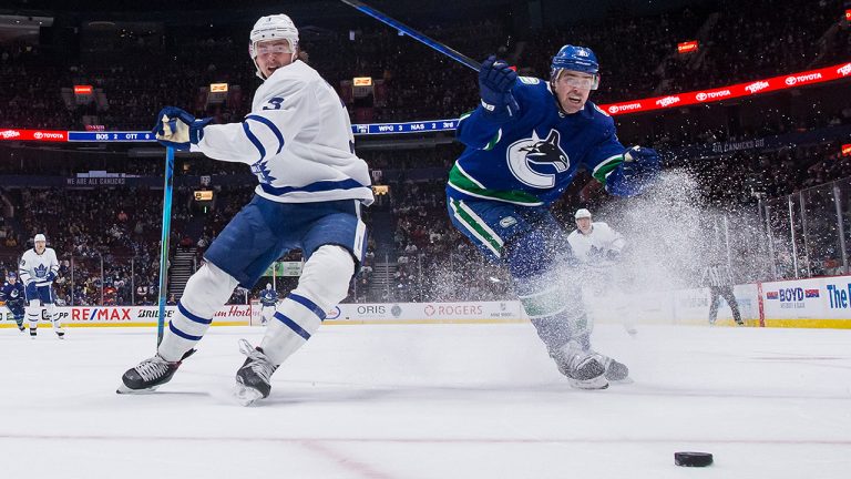 Toronto Maple Leafs' Justin Holl, left, and Vancouver Canucks' Tanner Pearson vie for the puck. (Darryl Dyck/CP)