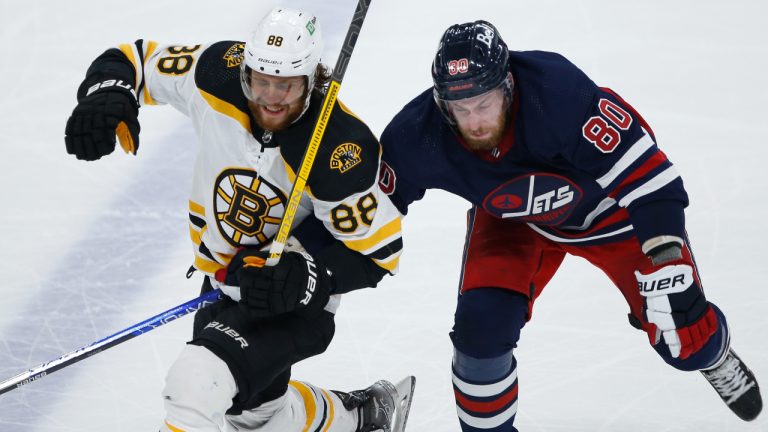 Winnipeg Jets' Pierre-Luc Dubois (80) and Boston Bruins' David Pastrnak (88) fight for position during third period NHL action in Winnipeg, Friday, March 18, 2022. (John Woods/AP)