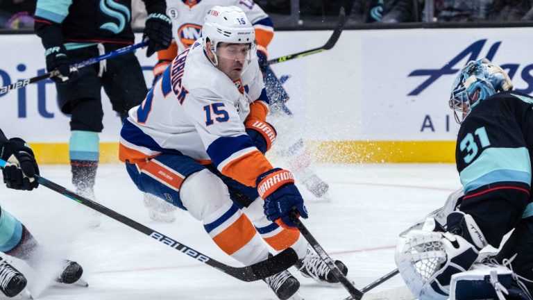 New York Islanders forward Cal Clutterbuck, left, skates against Seattle Kraken goalkeeper Philipp Grubauer during the first period of an NHL hockey game Tuesday, Feb. 22, 2022, in Seattle. The Islanders won 5-2. (Stephen Brashear/AP)