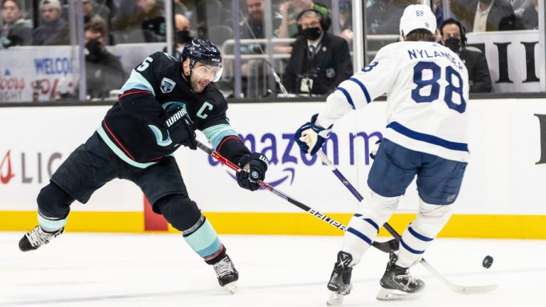 Seattle Kraken defenceman Mark Giordano, left, attempts to knock the puck away from Toronto Maple Leafs right wing William Nylander. (Stephen Brashear/AP)