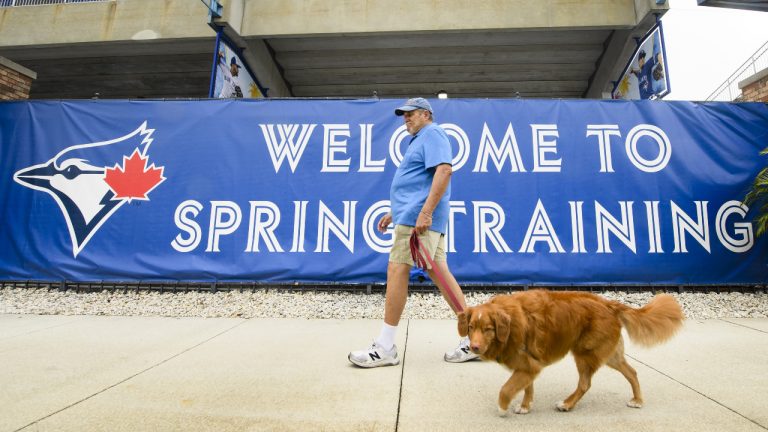 A man and his dog walk past the spring training home of the Toronto Blue Jays in Dunedin, Fla., on Monday, February 18, 2019. (Nathan Denette/CP)