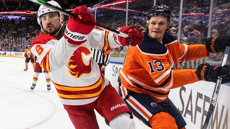 Calgary Flames' Christopher Tanev (8) checks Edmonton Oilers' Jesse Puljujarvi (13) during second period NHL action in Edmonton on Saturday, January 22, 2022. (Jason Franson/CP)