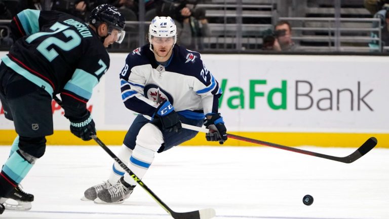 Winnipeg Jets' Nathan Beaulieu, right, watches as Seattle Kraken's Joonas Donskoi passes then puck in the second period of an NHL hockey game Thursday, Dec. 9, 2021, in Seattle. (Elaine Thompson/AP)