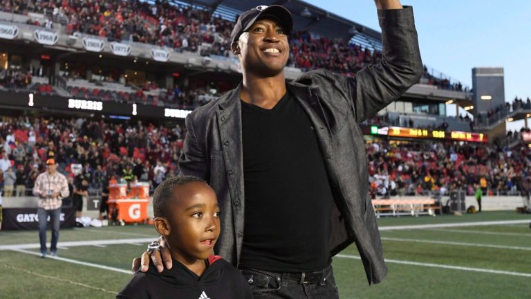 Former Ottawa Redblacks quarterback Henry Burris walks with his son during a ceremony honouring his career during the halftime of a CFL football game in Ottawa on Saturday, Sept. 9, 2017. (Justin Tang/CP)