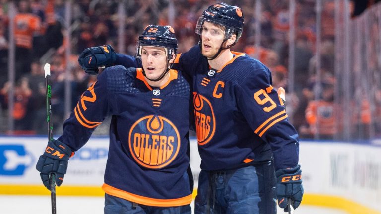 Edmonton Oilers' Tyson Barrie (22) and Connor McDavid (97) celebrate a goal against the Tampa Bay Lighting during second period NHL action in Edmonton on Saturday, March 12, 2022. (Jason Franson/CP)