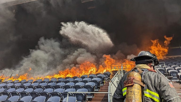 In this photo provided by the Denver Fire Department, firefighters battle flames at Empower Field at Mile High stadium in Denver, Thursday, March 24, 2022. Firefighters have extinguished a blaze that torched several rows of seats and a suite area at the Denver Broncos' stadium. The fire broke out in the third-level and burned at least six rows of seats in two sections. (Denver Fire Department via AP)