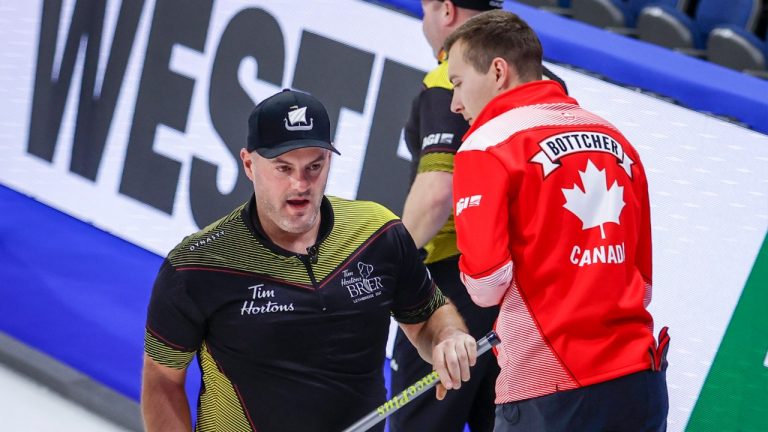 Team New Brunswick third Darren Moulding, left, passes former teammate Team Canada skip Brendan Bottcher at the Tim Hortons Brier in Lethbridge, Alta., Saturday, March 5, 2022. (Jeff McIntosh/CP)