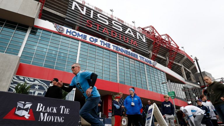 FILE - A Tennessee Titans fan runs a 40-yard dash outside Nissan Stadium before an NFL football game between the Titans and the Houston Texans on Nov. 21, 2021, in Nashville, Tenn. The Titans have gone from trying to modernize Nissan Stadium to working on plans for a brand-new stadium right next door after renovation costs more than doubled to $1.2 billion. (AP Photo/Wade Payne, File)