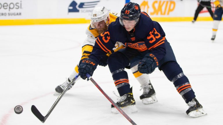 Nashville Predators' Mattias Ekholm (14) and Edmonton Oilers' Ryan Nugent-Hopkins (93) battle for the puck during second period NHL action in Edmonton on Thursday, January 27, 2022. (Jason Franson/CP)