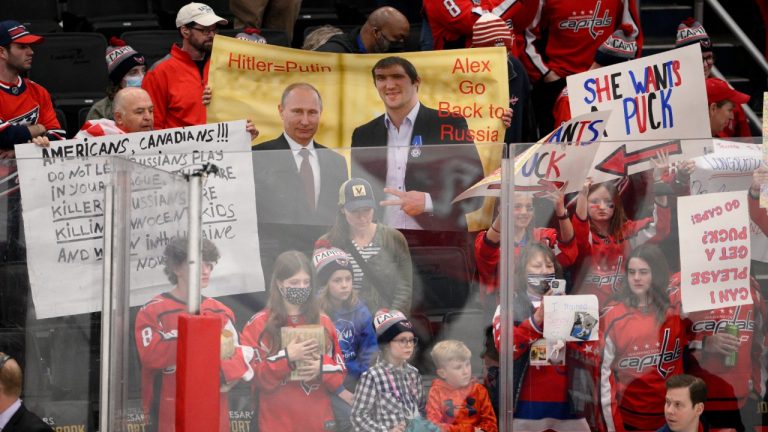 A sign is held up showing Vladimir Putin and Washington Capitals' Alex Ovechkin during warmups before an NHL hockey game between the Capitals and the Seattle Kraken, Saturday, March 5, 2022, in Washington. (Nick Wass/AP)