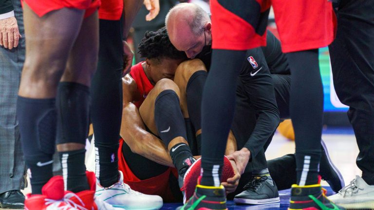 Toronto Raptors' Scottie Barnes, centre, gets looked over by the training staff after injuring his left leg during the second half of Game 1 of an NBA basketball first-round playoff series against the Philadelphia 76ers, Saturday, April 16, 2022, in Philadelphia. The 76ers won 131-111. (Chris Szagola/AP)