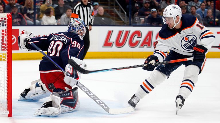 Columbus Blue Jackets goalie Elvis Merzlikins, left, stops a shot by Edmonton Oilers forward Zach Hyman during the first period an NHL hockey game in Columbus, Ohio, Sunday, April 24, 2022. (Paul Vernon/AP)