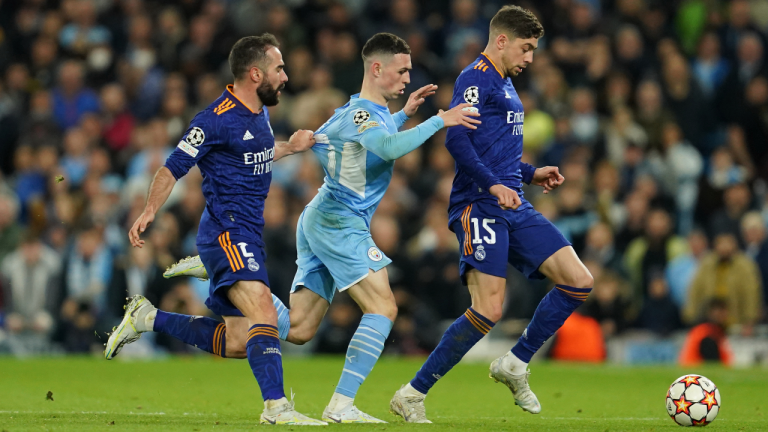 Manchester City's Phil Foden, center, fights for the ball with Real Madrid's Federico Valverde, right, and Real Madrid's Dani Carvajal the Champions League semi final, first leg soccer match between Manchester City and Real Madrid at the Etihad stadium in Manchester, England, Tuesday, April 26, 2022. (AP)