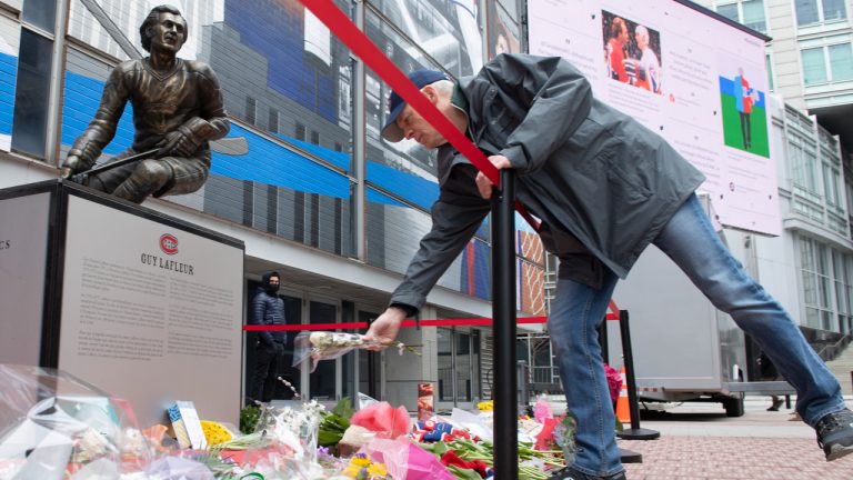 A man lays flowers in front of a statue of Montreal Canadiens legend Guy Lafleur outside the Bell Centre in Montreal, Saturday, April 23, 2022. Lafleur passed away on Friday at the age of 70. (Graham Hughes/CP)