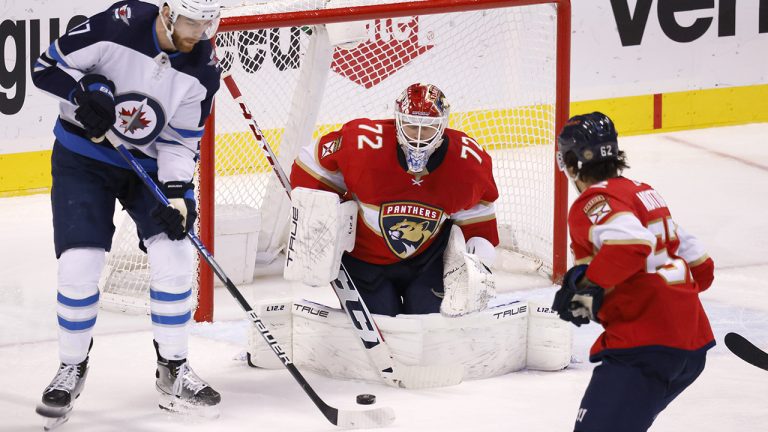 Winnipeg Jets centre Adam Lowry (17) tries to hit the puck over the pads of Florida Panthers goaltender Sergei Bobrovsky (72) as Panthers defenceman Brandon Montour (62) looks on. (Reinhold Matay/AP)