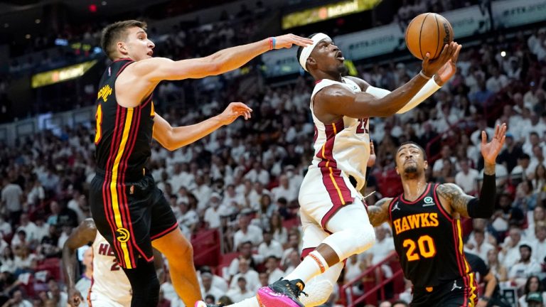 Miami Heat forward Jimmy Butler (22) goes to the basket as Atlanta Hawks guard Bogdan Bogdanovic, left, and forward John Collins (20) defend during the first half of Game 1 of an NBA basketball first-round playoff series, Sunday, April 17, 2022, in Miami. (Lynne Sladky/AP)