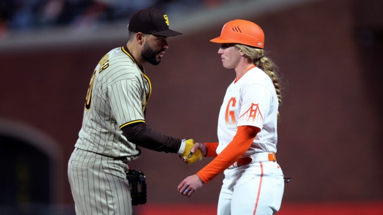 San Diego Padres first baseman Eric Hosmer, left, shakes hands with San Francisco Giants first base coach Alyssa Nakken during the third inning of a baseball game in San Francisco, Tuesday, April 12, 2022. (Jed Jacobsohn/AP Photo)