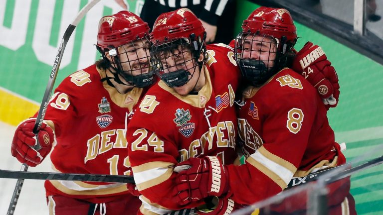 Denver's Carter Savoie (8) celebrates his winning goal with Bobby Brink (24) and Cole Guttman (19) in overtime during an NCAA men's Frozen Four semifinal hockey game against Michigan, Thursday, April 7, 2022, in Boston. (Michael Dwyer/AP)