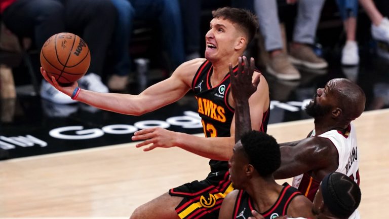 Atlanta Hawks guard Bogdan Bogdanovic (13) drives past Miami Heat center Dewayne Dedmon, top right, in the first half of an NBA playoff basketball game Sunday, April 24, 2022, in Atlanta. (John Bazemore/AP)