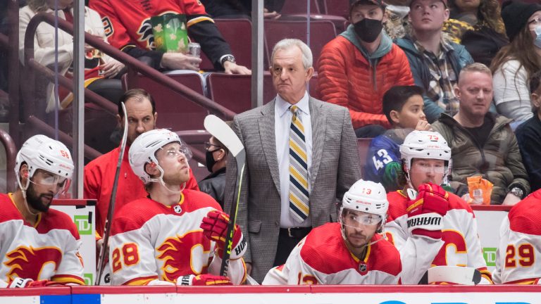 Calgary Flames head coach Darryl Sutter, back centre, stands on the bench behind Calgary Flames' Oliver Kylington, of Sweden, from left to right, Elias Lindholm, of Sweden, Johnny Gaudreau and Tyler Toffoli during the third period of an NHL hockey game in Vancouver, on Saturday, March 19, 2022. (Darryl Dyck/CP) 