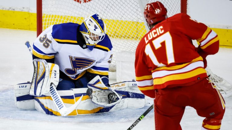 St. Louis Blues goalie Ville Husso, left, stops a shot from Calgary Flames Milan Lucic during second period NHL hockey action in Calgary, Saturday, April 2, 2022. (Jeff McIntosh/CP)