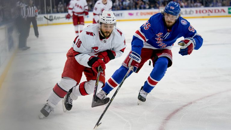 Carolina Hurricanes center Vincent Trocheck (16) and New York Rangers defenseman Ryan Lindgren (55) chase the puck in the first period of Game 4 of an NHL hockey Stanley Cup second-round playoff series, Tuesday, May 24, 2022, in New York. (John Minchillo/AP)