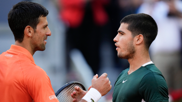 Novak Djokovic, left, shakes hands with Carlos Alcaraz at the end of a men's semifinal at the Mutua Madrid Open tennis tournament in Madrid, Spain, Saturday, May 7, 2022. Alcaraz won 6-7 (5-7), 7-5, 7-6 (7-5). (AP)