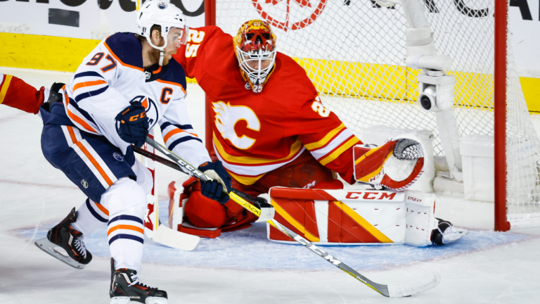 Edmonton Oilers centre Connor McDavid, left, tries to get the puck past Calgary Flames goalie Jacob Markstrom during first period NHL second-round playoff hockey action in Calgary, Thursday, May 26, 2022. (CP)