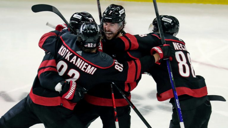 Carolina Hurricanes defenseman Ian Cole (28) celebrates his overtime goal against the New York Rangers with Jesperi Kotkaniemi (82), Martin Necas (88) and Brendan Smith (7) during Game 1 of an NHL hockey Stanley Cup second-round playoff series Wednesday, May 18, 2022 in Raleigh, N.C. (Chris Seward/AP)