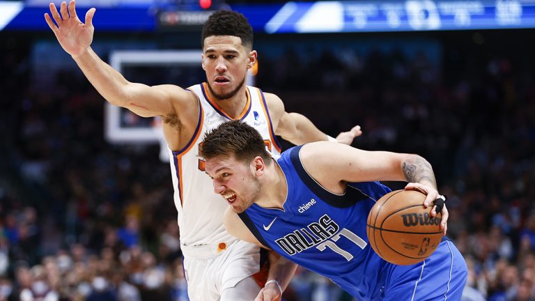 Dallas Mavericks guard Luka Doncic (77) battles Phoenix Suns guard Devin Booker for space during the second half of an NBA basketball game. (Brandon Wade/AP)