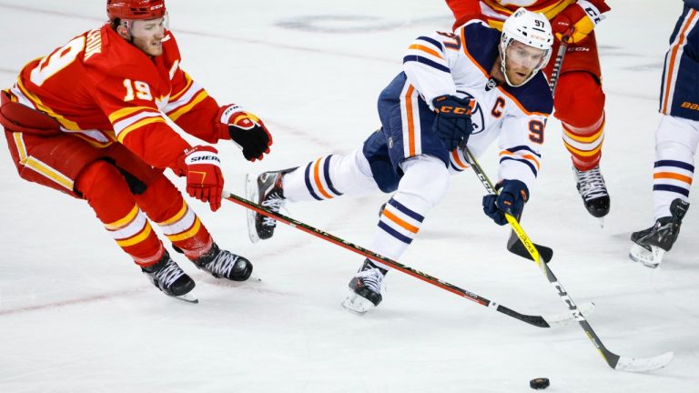 Edmonton Oilers centre Connor McDavid, right, passes the puck as Calgary Flames forward Matthew Tkachuk defends during first period NHL second round playoff hockey action in Calgary, Wednesday, May 18, 2022. (Jeff McIntosh/CP)