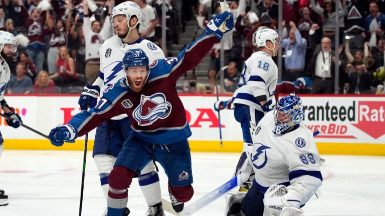 Colorado Avalanche left wing J.T. Compher, left, celebrates next to Tampa Bay Lightning goaltender Andrei Vasilevskiy, right, after an overtime goal by Andre Burakovsky in Game 1 of the NHL hockey Stanley Cup Final on Wednesday, June 15, 2022, in Denver. (AP Photo/John Locher)