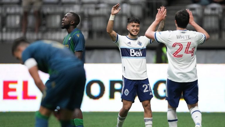 Vancouver Whitecaps' Ryan Raposo (27) and Brian White (24) celebrate White's first goal as York United's Chrisnovic N'sa, back left, looks on during the second half of a Canadian Championship semifinal soccer match, in Vancouver, on Wednesday, June 22, 2022. (Darryl Dyck/CP)