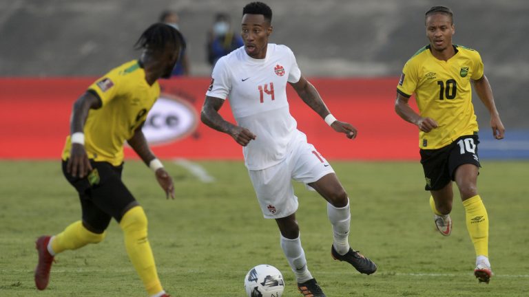 Canada's Mark Anthony Kaye, center, fights for the ball against Jamaica's Bobby Reid, right, and Oniel Fisher during a qualifying soccer match for the FIFA World Cup Qatar 2022 at the Independence Park stadium in Kingston, Jamaica, Sunday, Oct. 10, 2021. (Collin Reid/AP)