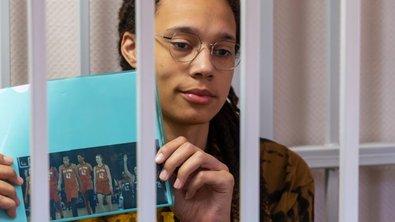 WNBA star and two-time Olympic gold medalist Brittney Griner holds up a photo of players from the recent all star game wearing her number, sitting in a cage at a court room prior to a hearing in the Khimki district court, just outside Moscow, Russia, Friday, July 15, 2022. Griner was arrested in February at the Russian capital's Sheremetyevo Airport when customs officials said they found vape canisters with cannabis oil in her luggage. She has been jailed since then, facing up to 10 years in prison if convicted. (Dmitry Serebryakov/AP)