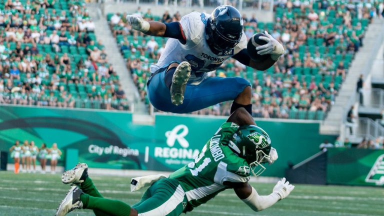 Toronto Argonauts running back Andrew Harris (33) attempts to hurdle over Saskatchewan Roughriders defensive back Nelson Lokombo (21) during the third quarter of CFL football action in Regina, on Sunday, July 24, 2022. (Heywood Yu/THE CANADIAN PRESS)