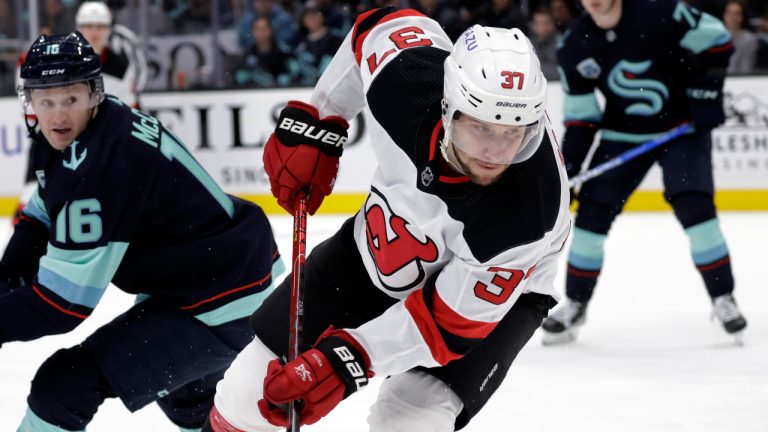 New Jersey Devils center Pavel Zacha (37) passes the puck with Seattle Kraken left wing Jared McCann (16) watching during the first period of an NHL hockey game Saturday, April 16, 2022, in Seattle. (John Froschauer/AP)